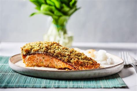A Piece Of Salmon On A Plate With White Rice And Green Flowers In The
