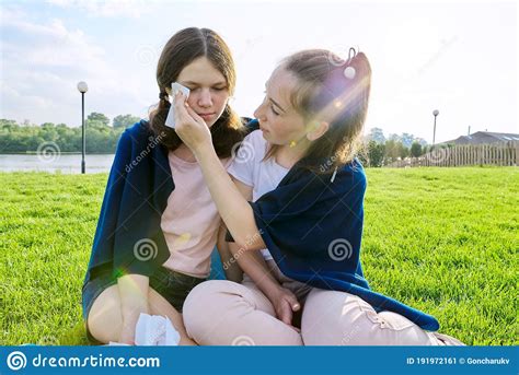 Crying Teenager Girl And Comforting Girlfriend Teenagers Sitting On