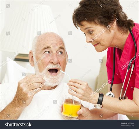 Home Health Nurse Giving Medicine To A Senior Patient Stock Photo