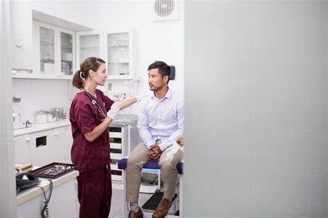 Female Doctor Talking With Male Patient In Clinic Examination Room