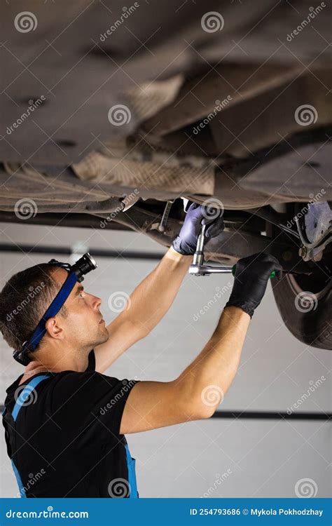 Handsome Professional Car Mechanic Is Working Under A Vehicle On A Lift
