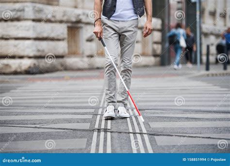 Midsection Of Young Blind Man With White Cane Walking Across The Street