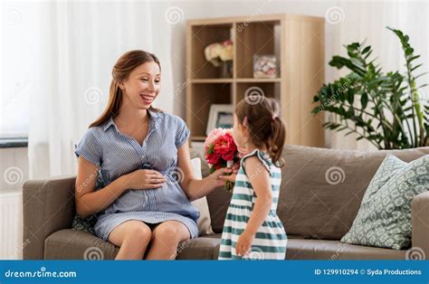 Muchacha Que Da Las Flores A Su Madre Embarazada En Casa Foto De