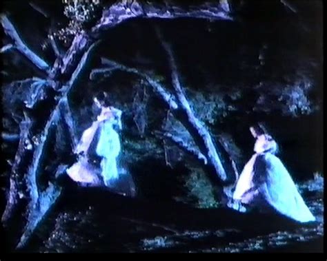 Two Women In Blue Dresses Are Walking Through The Woods At Night One