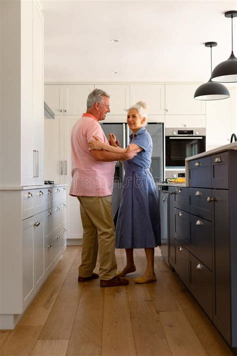 Happy Caucasian Senior Couple Dancing Together In Kitchen And Having