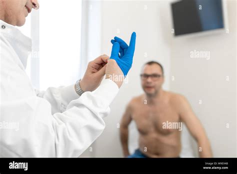 Doctor Urologist Puts A Medical Glove On The Arm To Examine The Patient