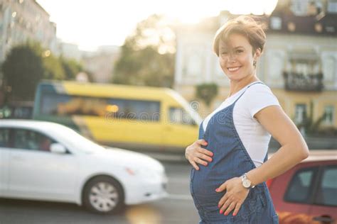 Smiling Pregnant Middle Aged Woman Sits On Steps In The Street Stock