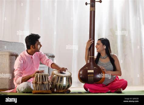 Young Man And Woman Playing Tabla And Tanpura Together At Home Stock