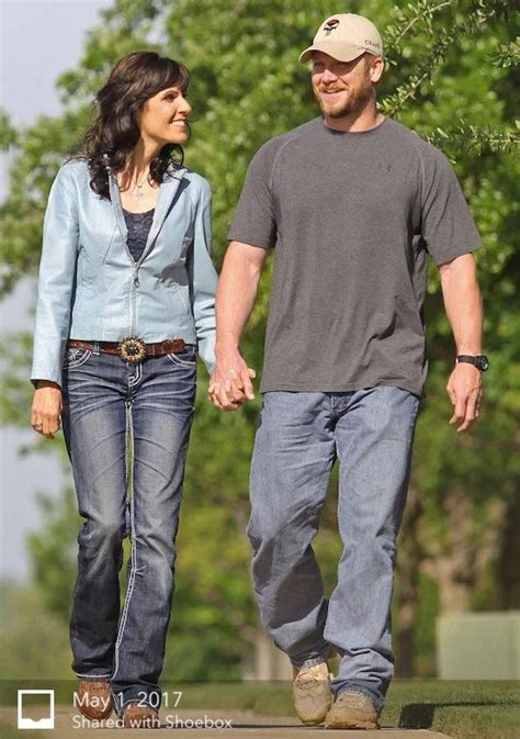 A Man And Woman Walking Down The Street Holding Hands With Trees In The