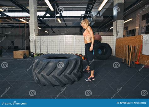Female Athlete Performing Tire Flipping Crossfit Exercise