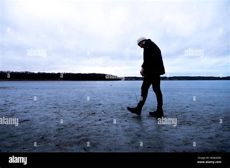 A Young Man Walks Across An Icy Lake With His Head Hanging Down Stock