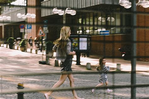 Mother And Daughter Running Along The Street By Evgenij Yulkin