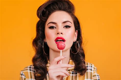 Closeup View Of Woman Licking Lollipop Pinup Girl With Curly Hairstyle Holding Candy On Yellow