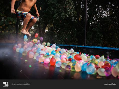 Child Jumping On Trampoline Filled With Water Balloons Stock Photo Offset