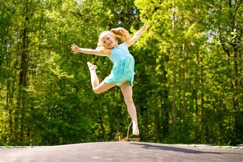 Free Photo A Happy Girl In A Dress Jumps On A Trampoline In A Park On