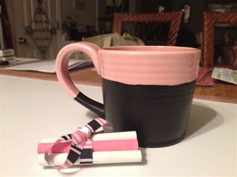 A Pink And Black Coffee Mug Sitting On Top Of A Table Next To Two