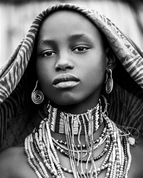 An African Woman With Jewelry On Her Neck And Headdress Looking At The