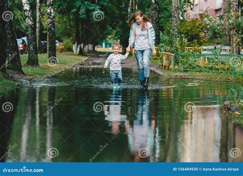 Mother And Her Toddler Walking Through A Puddle Stock Photo Image Of