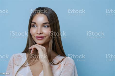 Portrait Of Good Looking Woman Touches Chin And Has Thoughtful