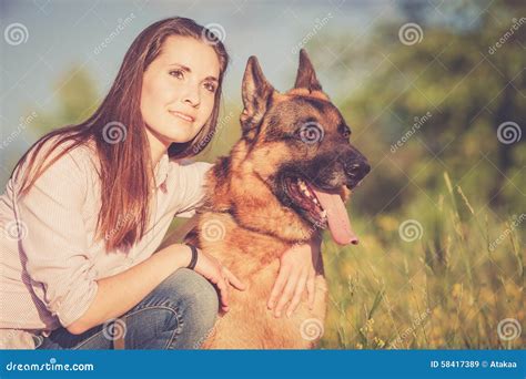 Young Beautiful Girl With A German Shepherd Playing On The Lawn Stock