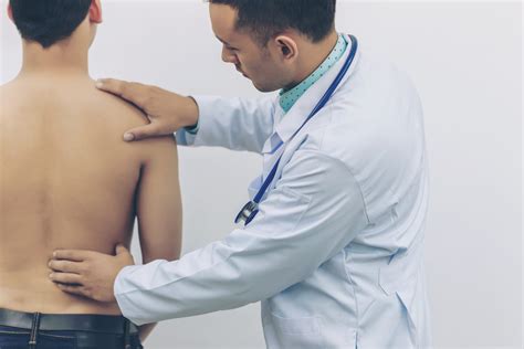 Doctor Touches The Back Plate For Causes Of Back Pain With Stethoscope