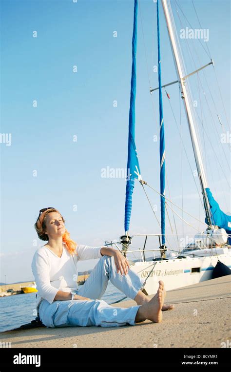 Woman Relaxing On Harbor Next To Boat Stock Photo Alamy