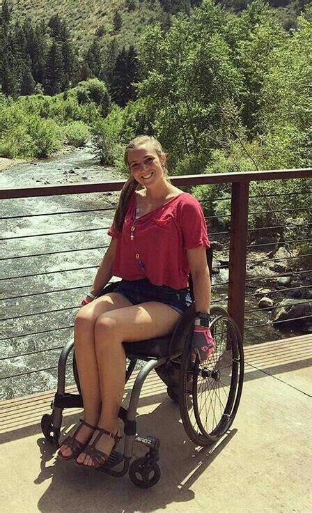 A Woman Sitting In A Wheel Chair On A Bridge Next To A River And Mountains