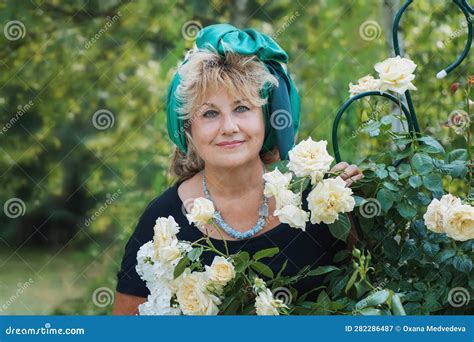 59 Year Old Woman In The Garden A Mature Woman Enjoys The Flowers Of A