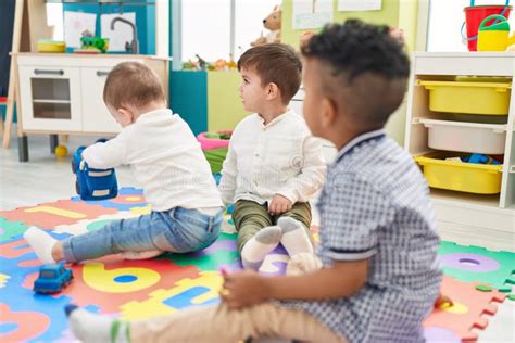 Group Of Kids Playing With Cars Toys Sitting On Floor At Kindergarten