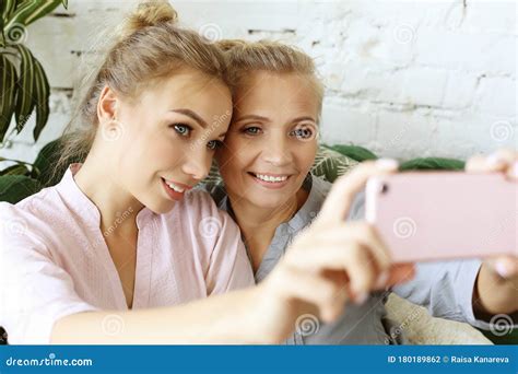 Portrait Of Beautiful Mature Mother And Her Daughter Making A Selfie Using Smart Phone And