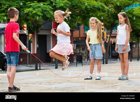 Happy Kids In School Age Playing Together With Jumping Rope Outdoors