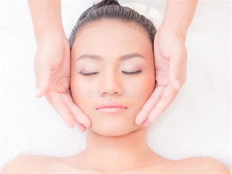 A Beautiful Asian Woman Closes Her Eyes Relaxes In A Spa Shop With A Facial Massage From A