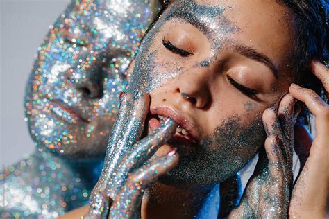 Shiny Model Spreading Glitter On Face Of Woman Lgbtqia By Stocksy
