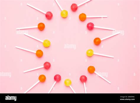 Pink Orange And Yellow Sweet Candy Lolipop On A Pastel Pink Background