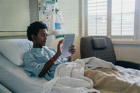 Black Boy In Hospital Bed Listening To Digital Tablet Stock Photo