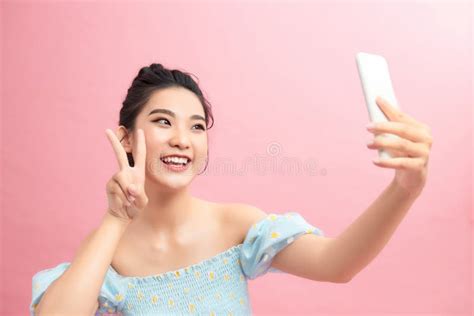 Positive Pretty Woman Holding Camera With Extended Arm Showing Peace