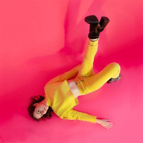 A Woman Laying On The Ground With Her Legs Up In The Air And Wearing Yellow