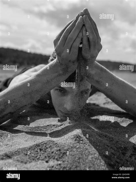 Man Lying On His Stomach And Pouring Sand Through Hands In The Desert