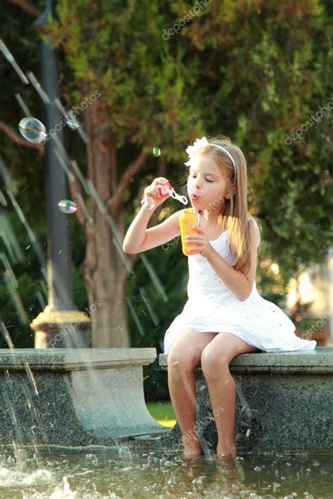 Little Girl Playing And Having Fun Enjoying The Spray Of The Fountain