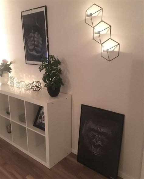 A White Shelf With Some Plants And Pictures On It