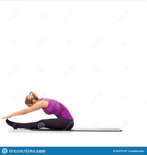 Touching Her Toes A Young Woman Sitting On A Mat And Stretching To