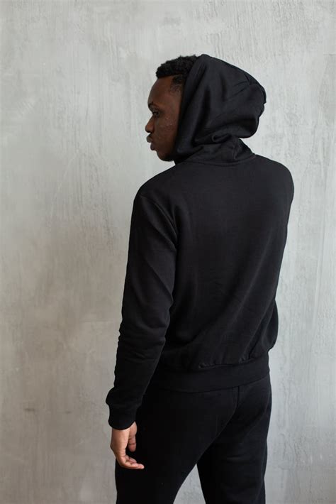 Serious Black Man In Hoodie And Pants Against Gray Wall · Free Stock Photo
