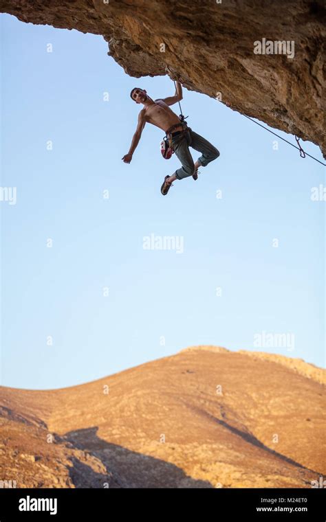 Male Rock Climber Hanging With One Hand On Cliff Man Climbing Over