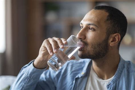 Portrait Of Handsome Young Black Man Drinking Water From Glass Stock