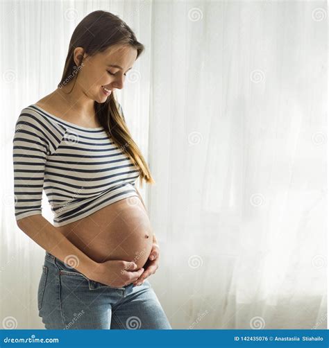 Happy Attractive Pregnant Woman Standing Near The Window And Holding Her Belly 库存照片 图片 包括有 预计