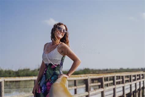 Portrait Of Young Beautiful Woman Standing On A Wood Pier In A Natural Park At Sunset Tourism