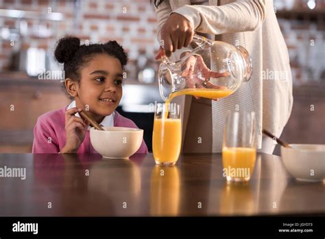 Mother Pouring Juice Into Babe S Glass During Breakfast At Home Stock Photo Alamy