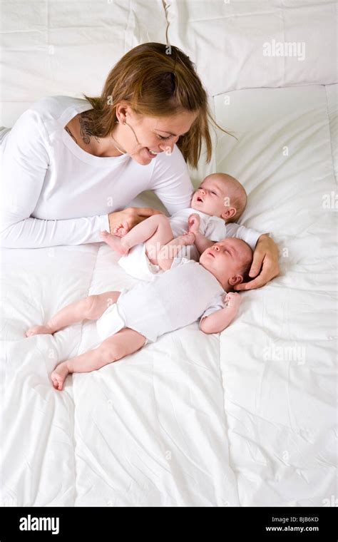 Mother With Newborn Twins Lying On Bed One Sleeping Stock Photo Alamy