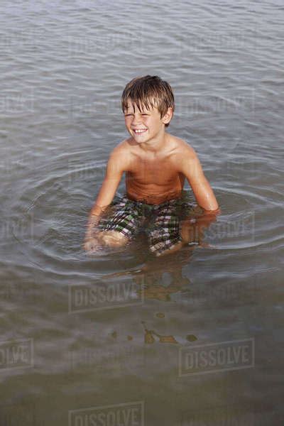 Boy Sitting In Shallow Water Stock Photo Dissolve