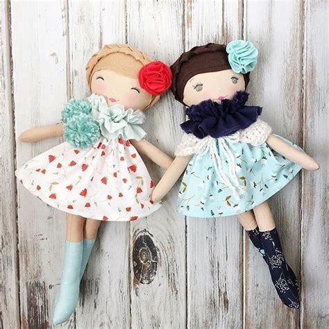 Two Dolls Sitting Next To Each Other On A Wooden Surface